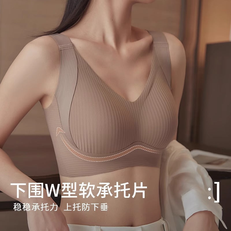 A woman wearing a ribbed, wireless bra in a warm taupe-beige color, shown from the chest up in an indoor setting. Chinese text is overlaid at the bottom describing the product as a soft承托片 with W-shaped support.